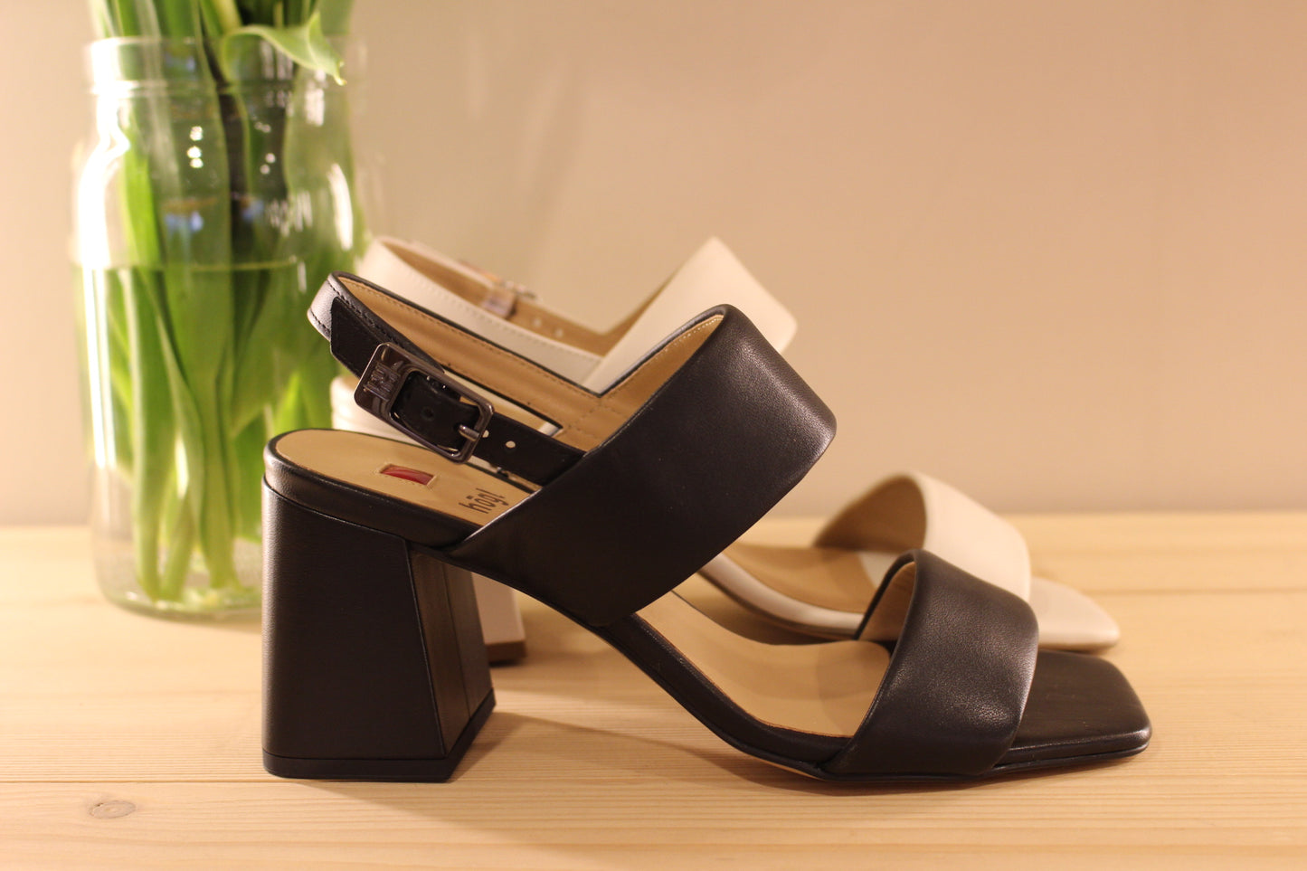 Fabrication autrichienne. Sandale en cuir de couleur ivoire ou noir. Serrage par boucle sur bride arrière. Chaussures doublées cuir. Semelle interne en cuir. Semelle externe en élastomère. Talon enrobé cuir ton sur ton de 6.5 cm.