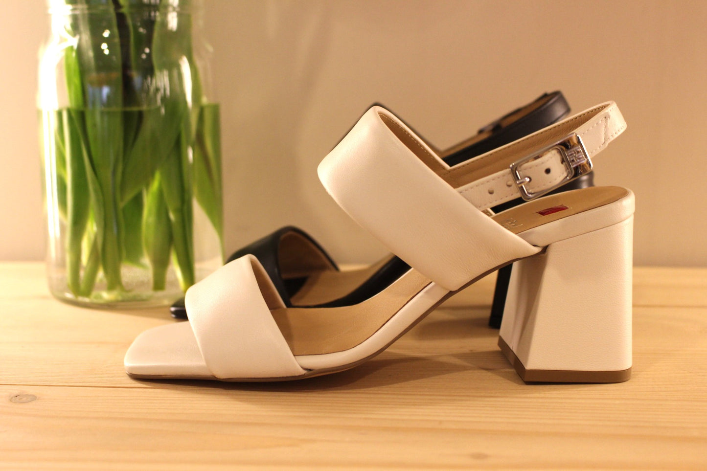 Fabrication autrichienne. Sandale en cuir de couleur ivoire ou noir. Serrage par boucle sur bride arrière. Chaussures doublées cuir. Semelle interne en cuir. Semelle externe en élastomère. Talon enrobé cuir ton sur ton de 6.5 cm.