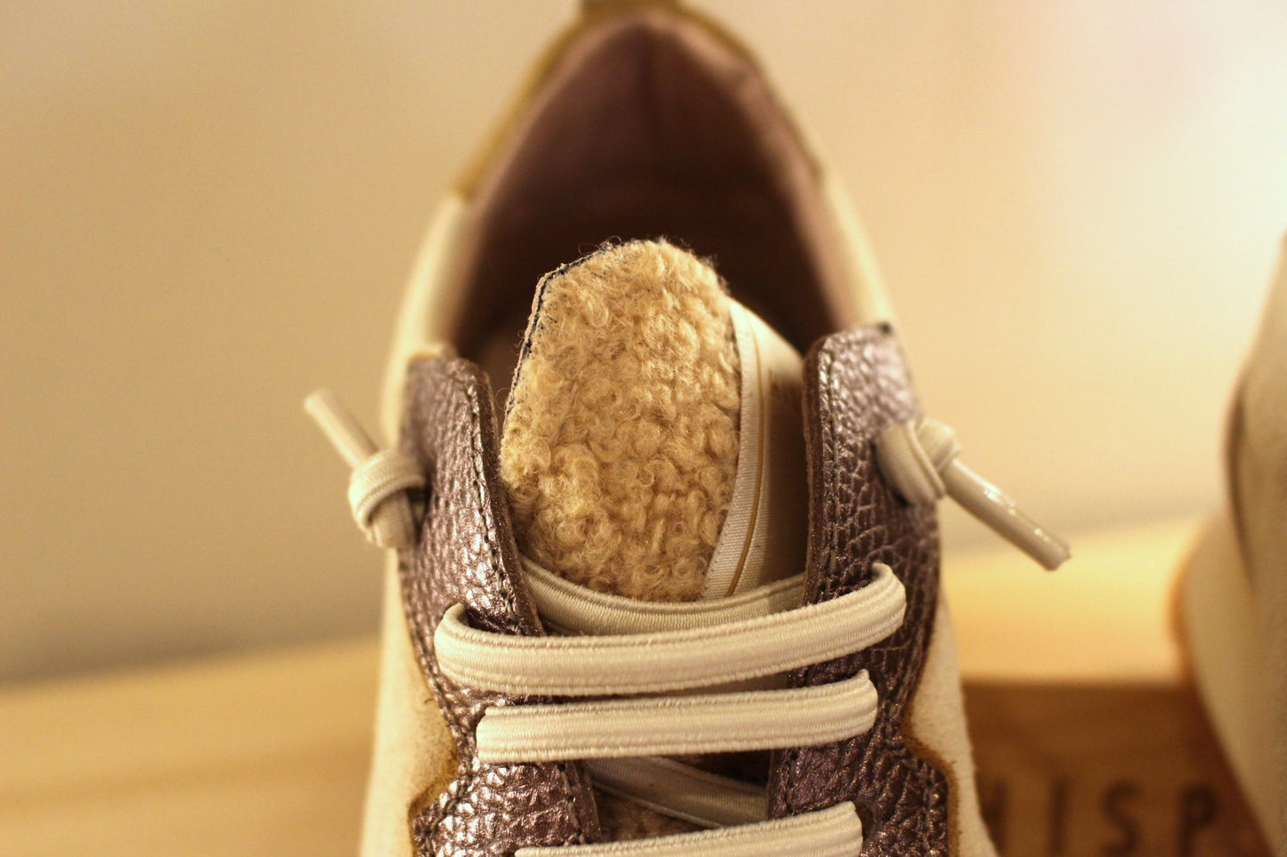 Basket en cuir de couleur crème et métallisé étain. Languette en laine bouclette ton sur ton. Lacets élastiqués beige.