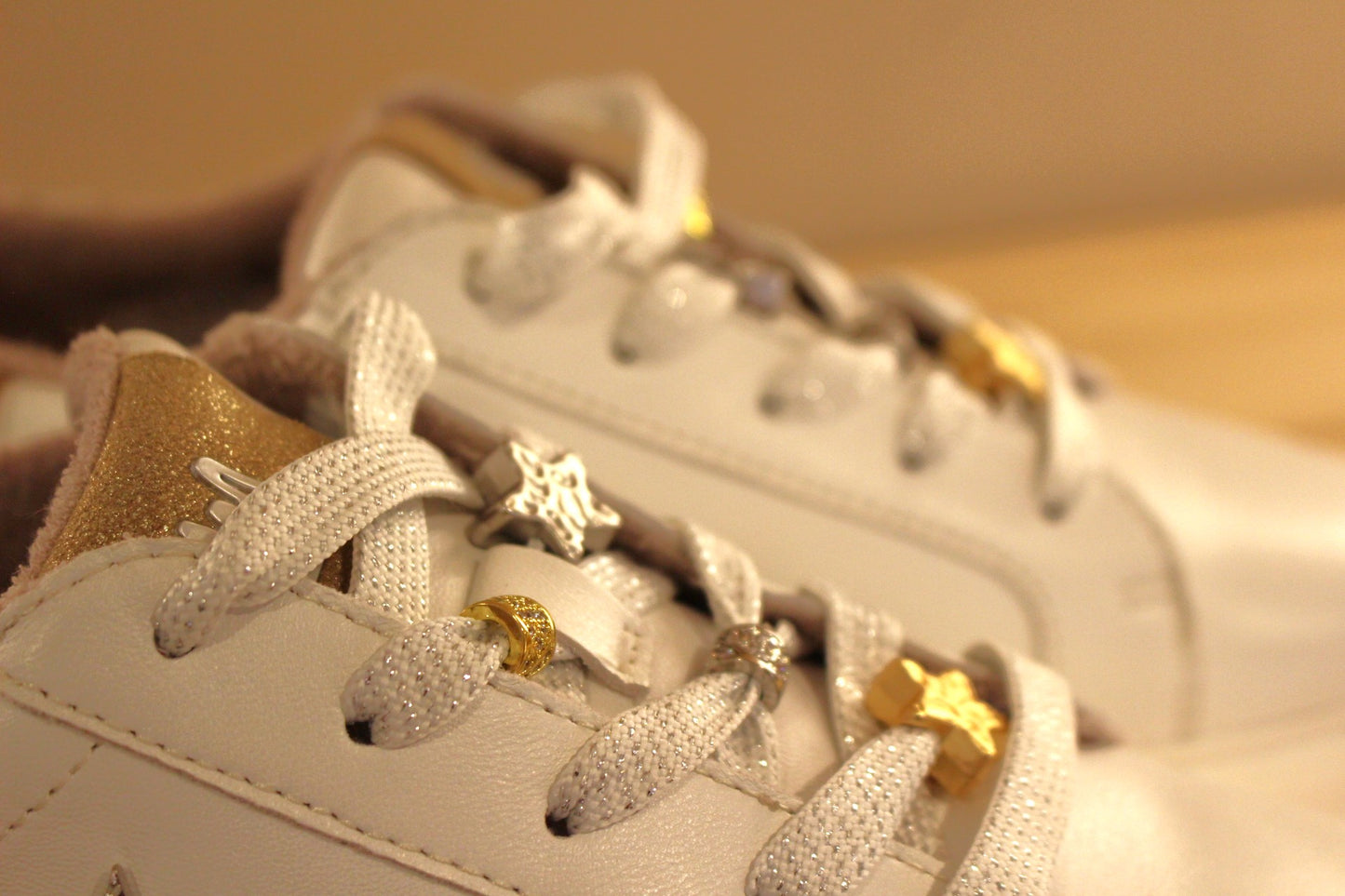 Sneaker MAMZELLE en cuir lisse de couleur blanche. Bijoux décoratifs sur le quartier externe et sur les lacets