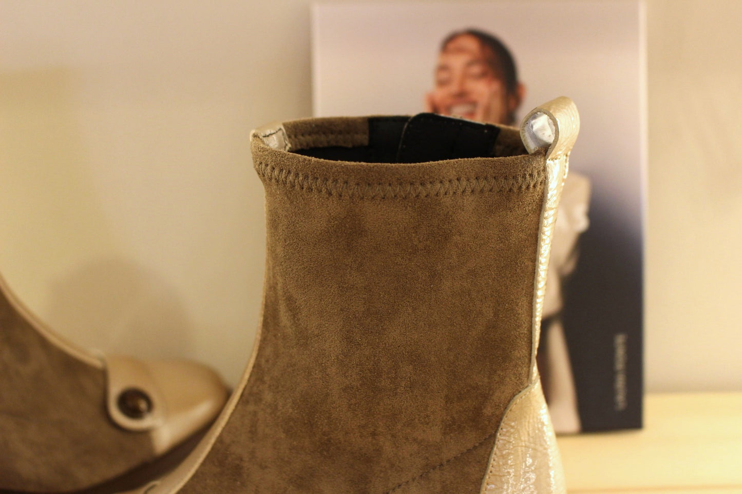 Bottine en cuir lisse de couleur crème avec une patine légèrement bruni. Bride vernis crème et bouton étain sur le coup de pied. Tige en velours taupe avec arrière vernis.
