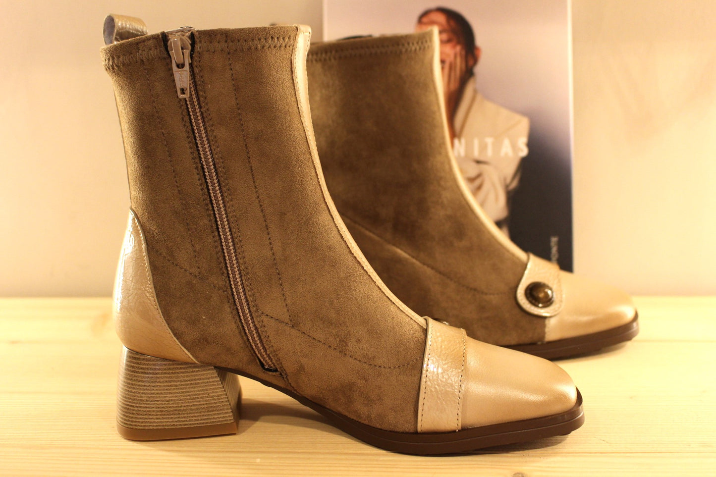 Bottine en cuir lisse de couleur crème avec une patine légèrement bruni. Bride vernis crème et bouton étain sur le coup de pied. Tige en velours taupe avec arrière vernis.