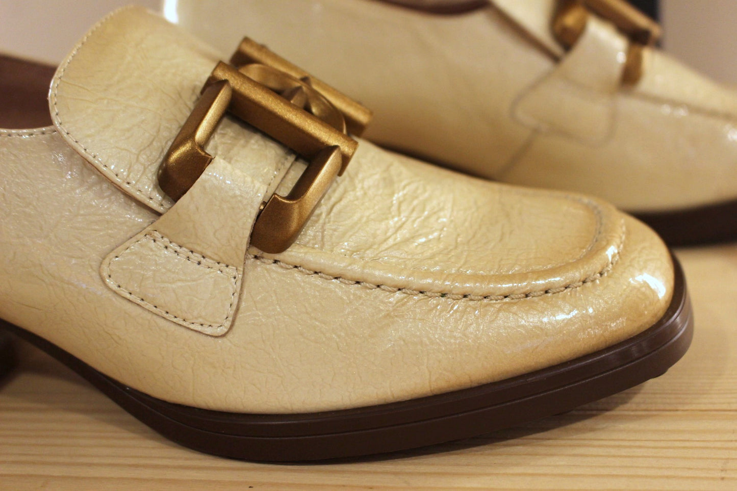 Mocassins en cuir vieillit, vernis de couleur crème avec une patine légèrement bruni. Boucle déco sur le coup de pied.