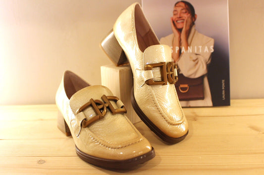 Mocassins en cuir vieillit, vernis de couleur crème avec une patine légèrement bruni. Boucle déco sur le coup de pied.