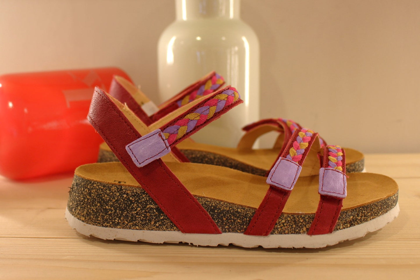 Sandales THINK en cuir de couleur rouge fraise. Habillage des brides en tressé de cuirs colorés parme, rouge et jaune. Serrage par trois scratchs. Chaussures extra légères. Semelle interne anatomique