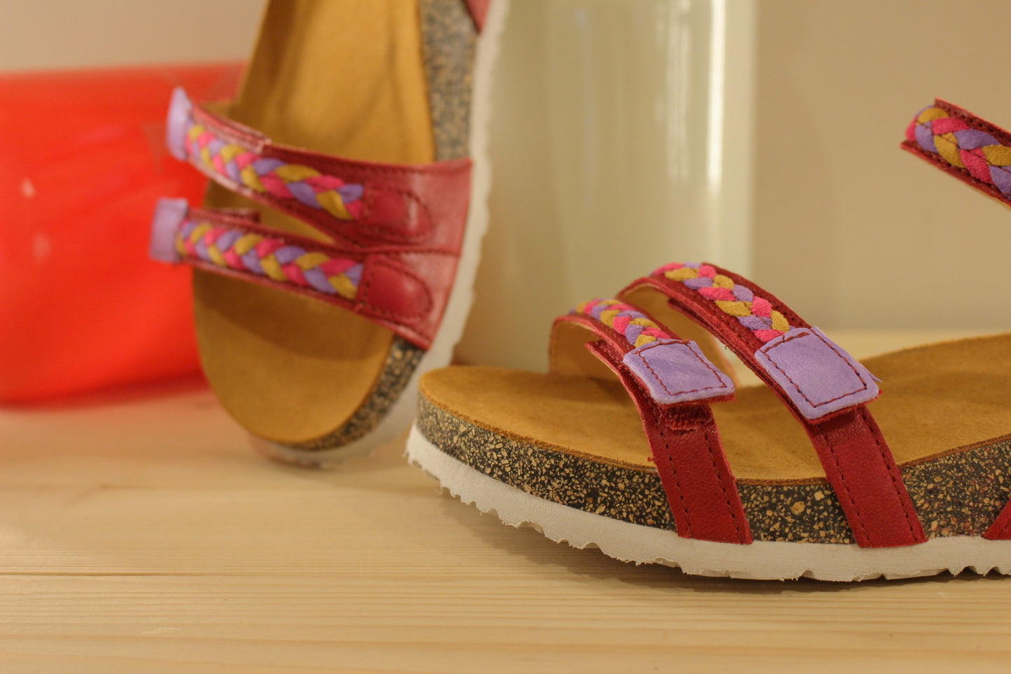 Sandales THINK en cuir de couleur rouge fraise. Habillage des brides en tressé de cuirs colorés parme, rouge et jaune. Serrage par trois scratchs. Chaussures extra légères. Semelle interne anatomique