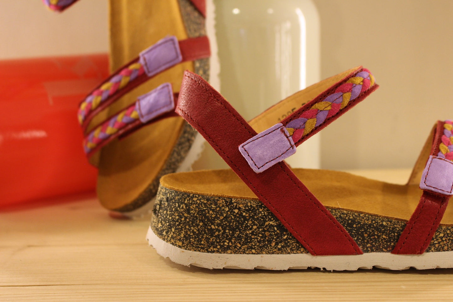 Sandales THINK en cuir de couleur rouge fraise. Habillage des brides en tressé de cuirs colorés parme, rouge et jaune. Serrage par trois scratchs. Chaussures extra légères. Semelle interne anatomique