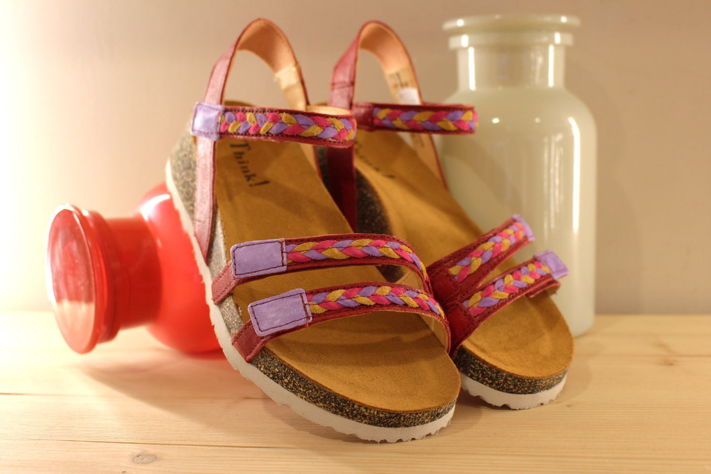 Sandales THINK en cuir de couleur rouge fraise. Habillage des brides en tressé de cuirs colorés parme, rouge et jaune. Serrage par trois scratchs. Chaussures extra légères. Semelle interne anatomique