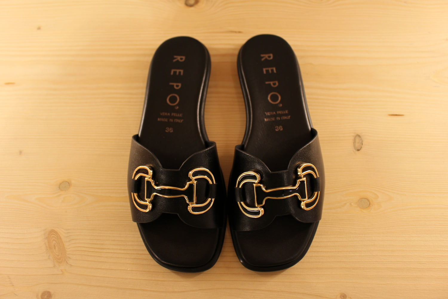 Mules en cuir de couleur noir. Habillage boucle noir et doré décoratif REPO