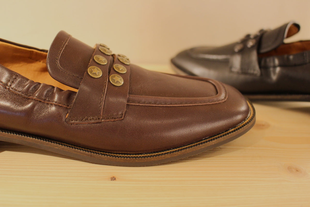 Mocassins Mamzelle en cuir de couleur noir ou moka. Habillage clous étoilés sur la barette coup de pied