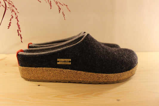 Chaussons HAFLINGER coupe sabot en pure laine de couleur graphit avec un double contour de coup de pied de couleur gris clair. Retour à l'arrière assez montant pour permettre un meilleur maintien à la marche