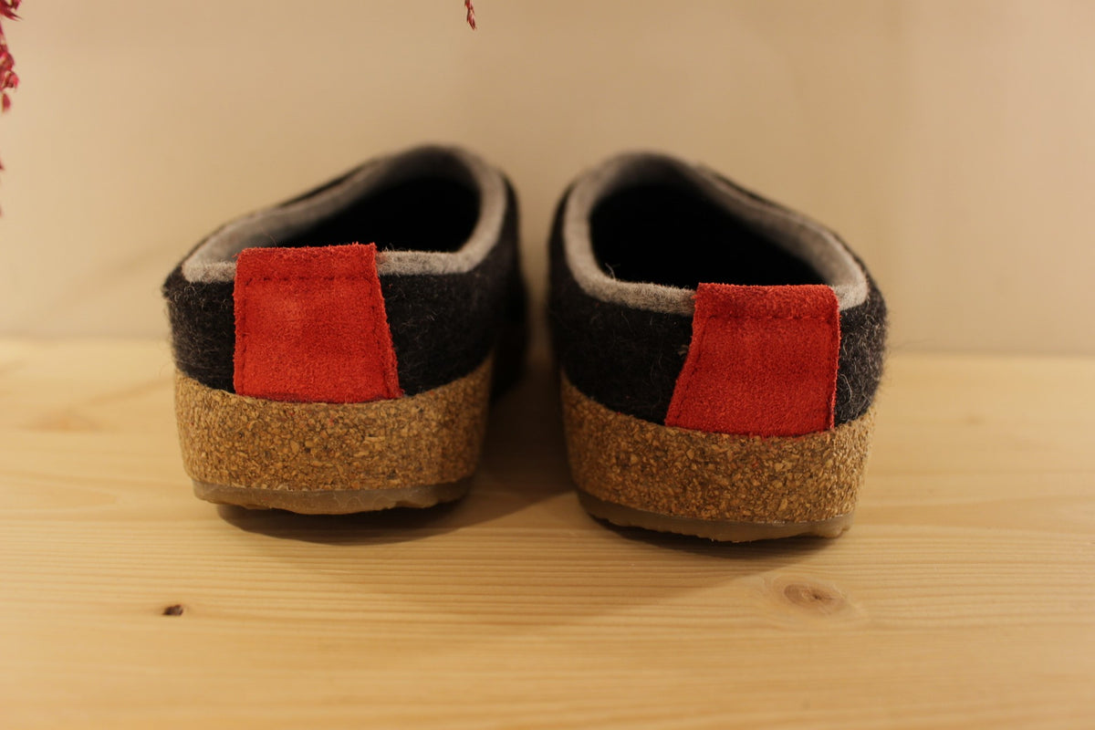 Chaussons HAFLINGER coupe sabot en pure laine de couleur graphit avec un double contour de coup de pied de couleur gris clair. Retour à l'arrière assez montant pour permettre un meilleur maintien à la marche