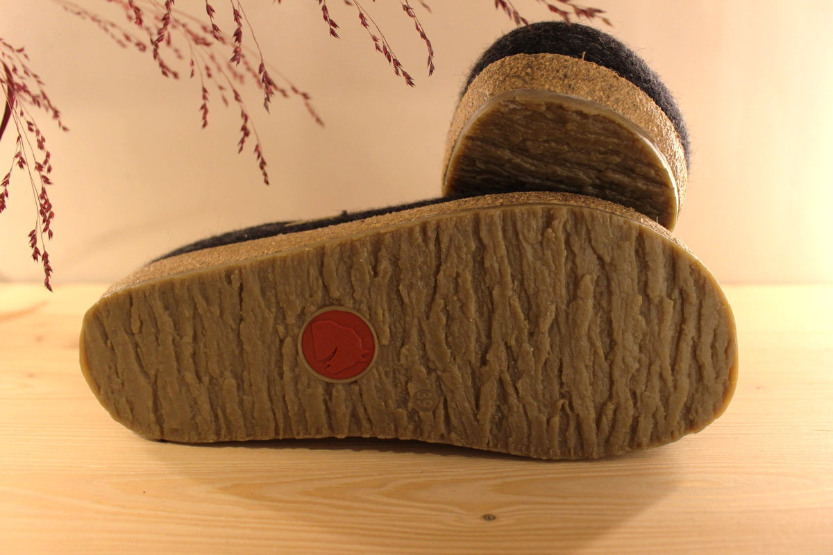 Chaussons HAFLINGER coupe sabot en pure laine de couleur graphit avec un double contour de coup de pied de couleur gris clair. Retour à l'arrière assez montant pour permettre un meilleur maintien à la marche