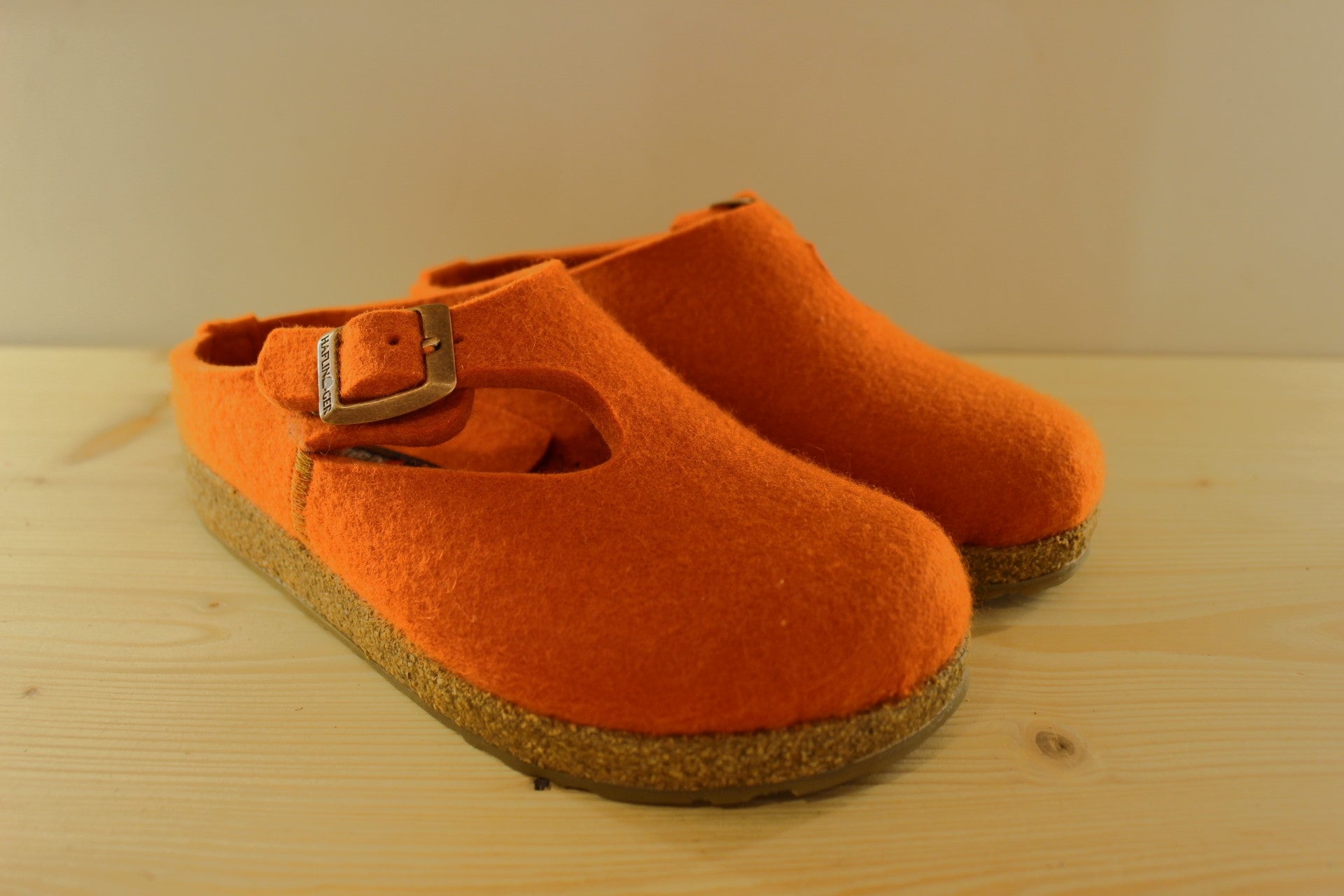 Chaussons HAFLINGER coupe sabot en pur laine de couleur orange. Serrage par boucle sur bride coup de pied