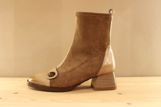 Bottine en cuir lisse de couleur crème avec une patine légèrement bruni. Bride vernis crème et bouton étain sur le coup de pied. Tige en velours taupe avec arrière vernis. Zip du côté interne.