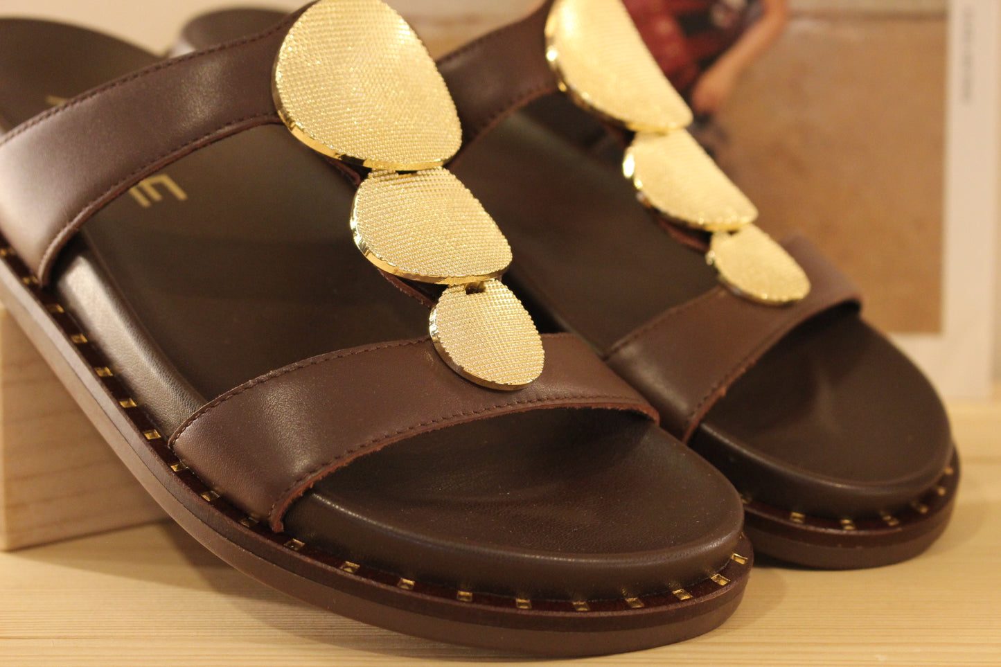 Mule ALPE en cuir de couleur chocolat. Habillage médaillon métallisé platine imprimé sur la bride salomé.