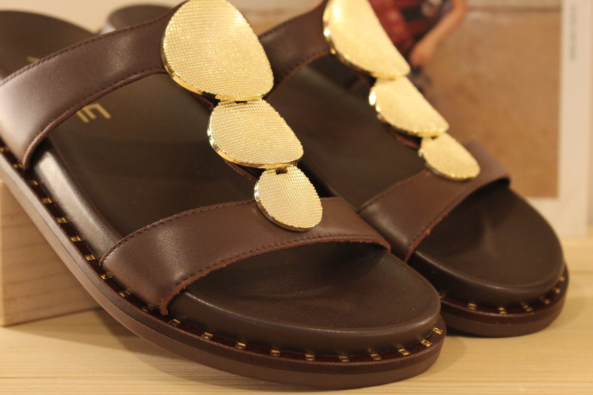 Mule ALPE en cuir de couleur chocolat. Habillage médaillon métallisé platine imprimé sur la bride salomé.