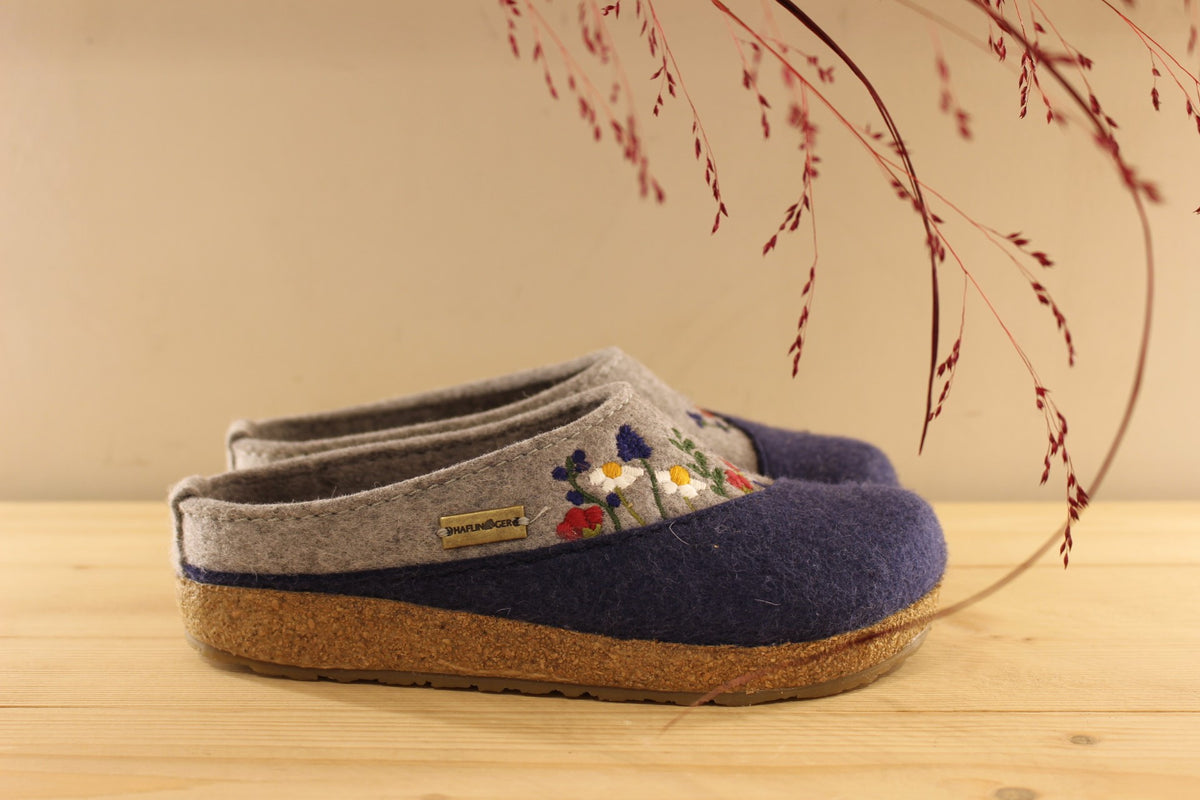 Chaussons HAFLINGER coupe sabot en pure laine de couleur gris anthracite et bleu chiné. Déco florale sur le coup de pied