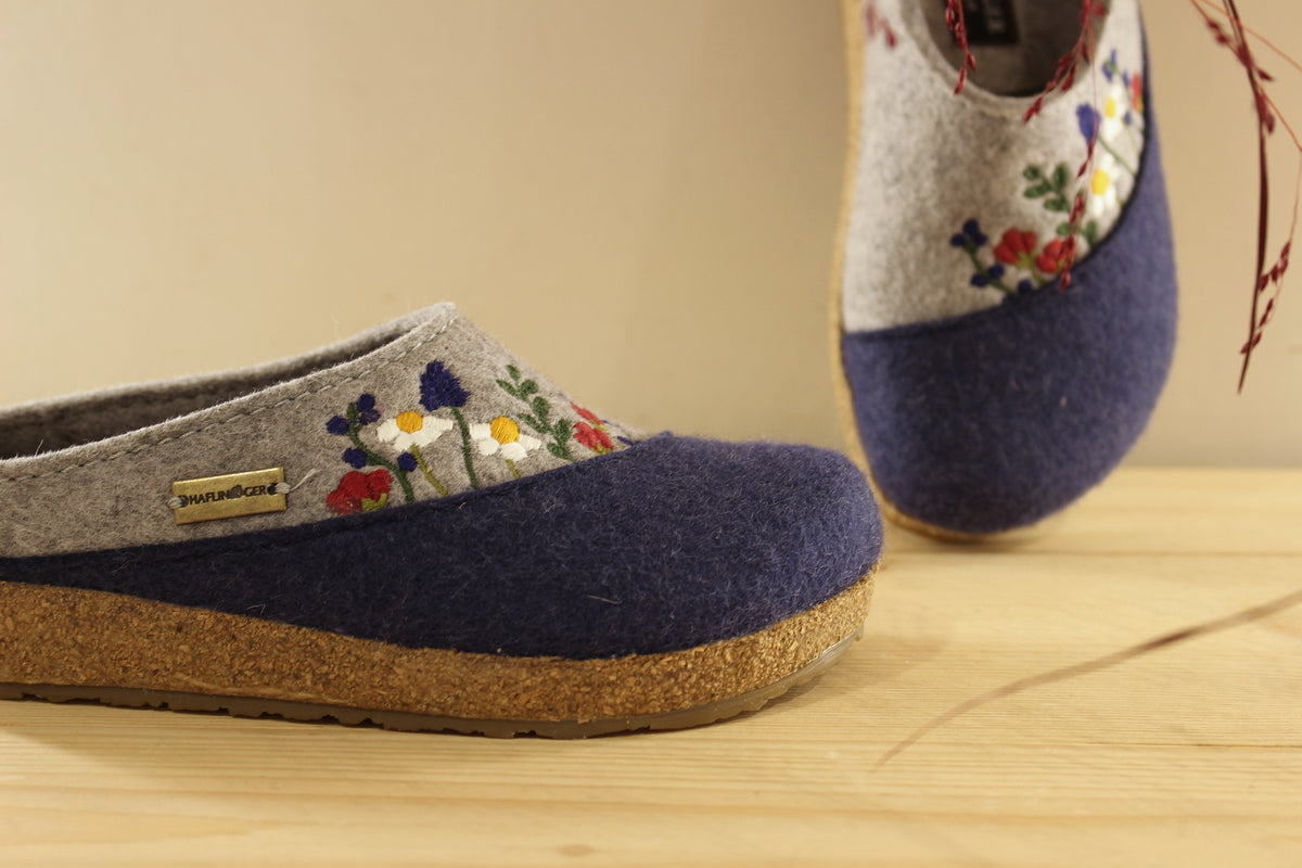 Chaussons HAFLINGER coupe sabot en pure laine de couleur gris anthracite et bleu chiné. Déco florale sur le coup de pied