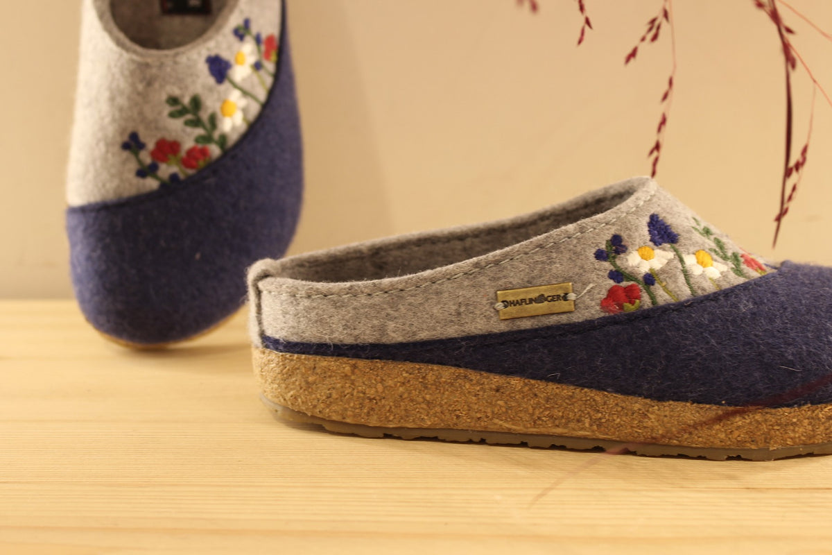 Chaussons HAFLINGER coupe sabot en pure laine de couleur gris anthracite et bleu chiné. Déco florale sur le coup de pied