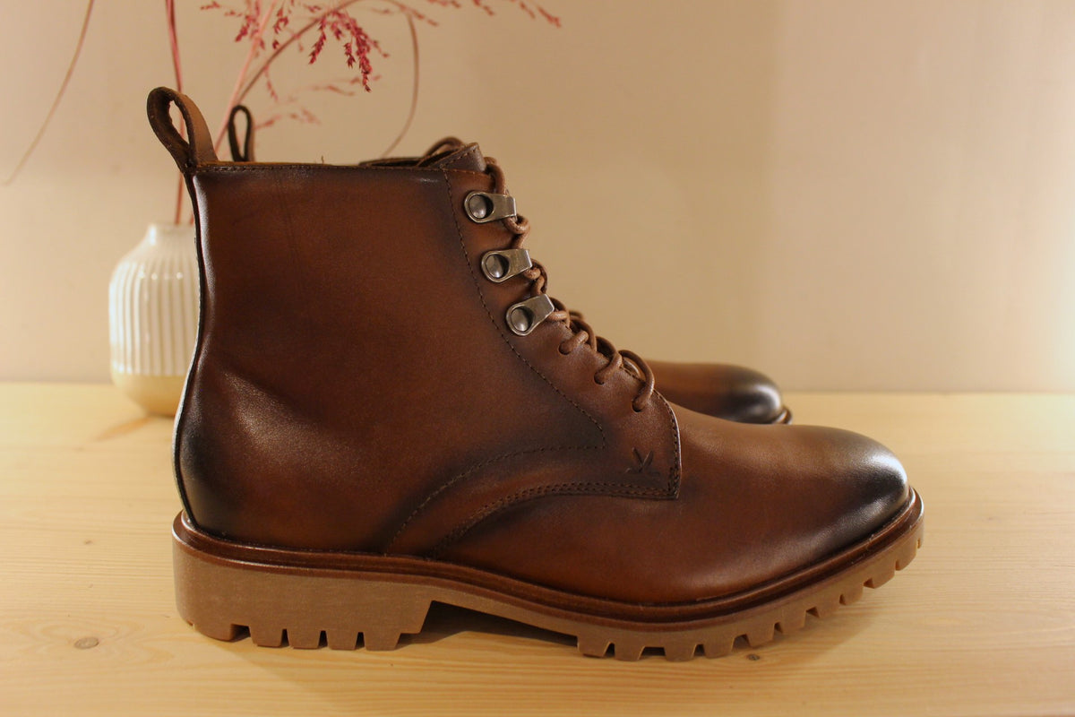 Bottines Lloyd en cuir de couleur cognac avec le bout bruni. Serrage lacets avec finition crochets. Zip du côté interne