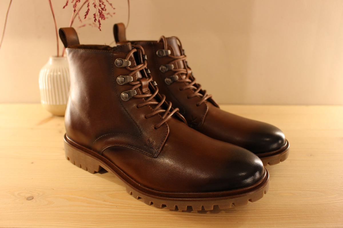 Bottines Lloyd en cuir de couleur cognac avec le bout bruni. Serrage lacets avec finition crochets. Zip du côté interne
