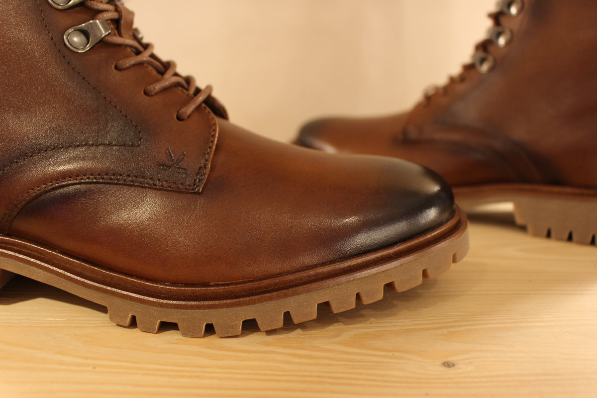 Bottines Lloyd en cuir de couleur cognac avec le bout bruni. Serrage lacets avec finition crochets. Zip du côté interne