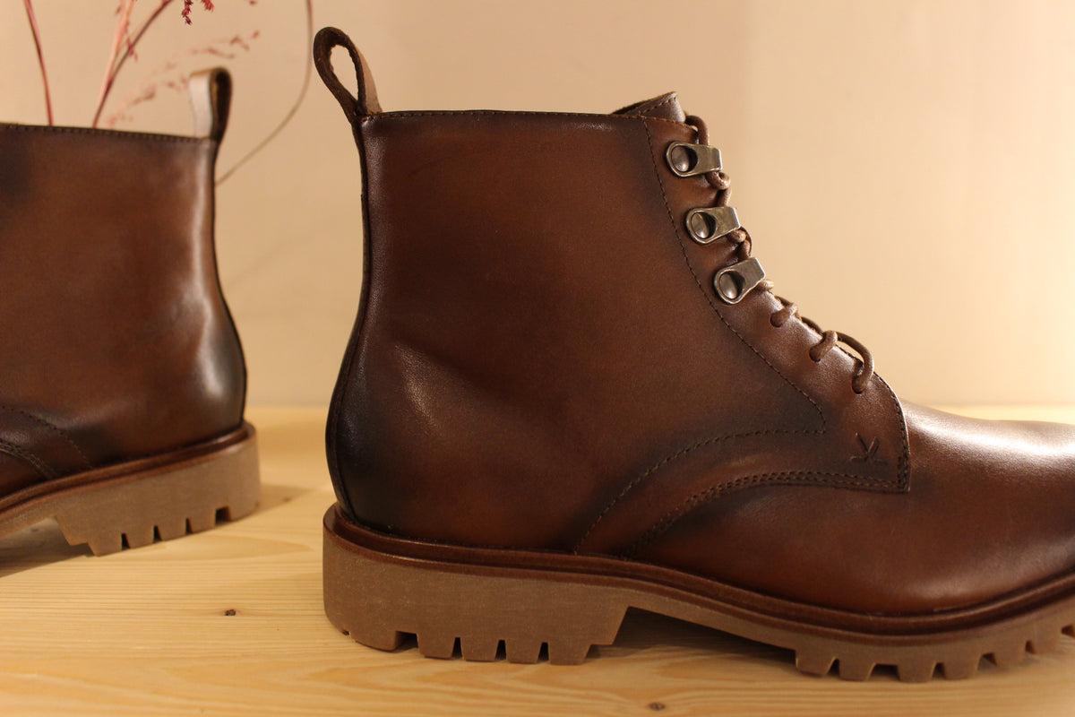 Bottines Lloyd en cuir de couleur cognac avec le bout bruni. Serrage lacets avec finition crochets. Zip du côté interne