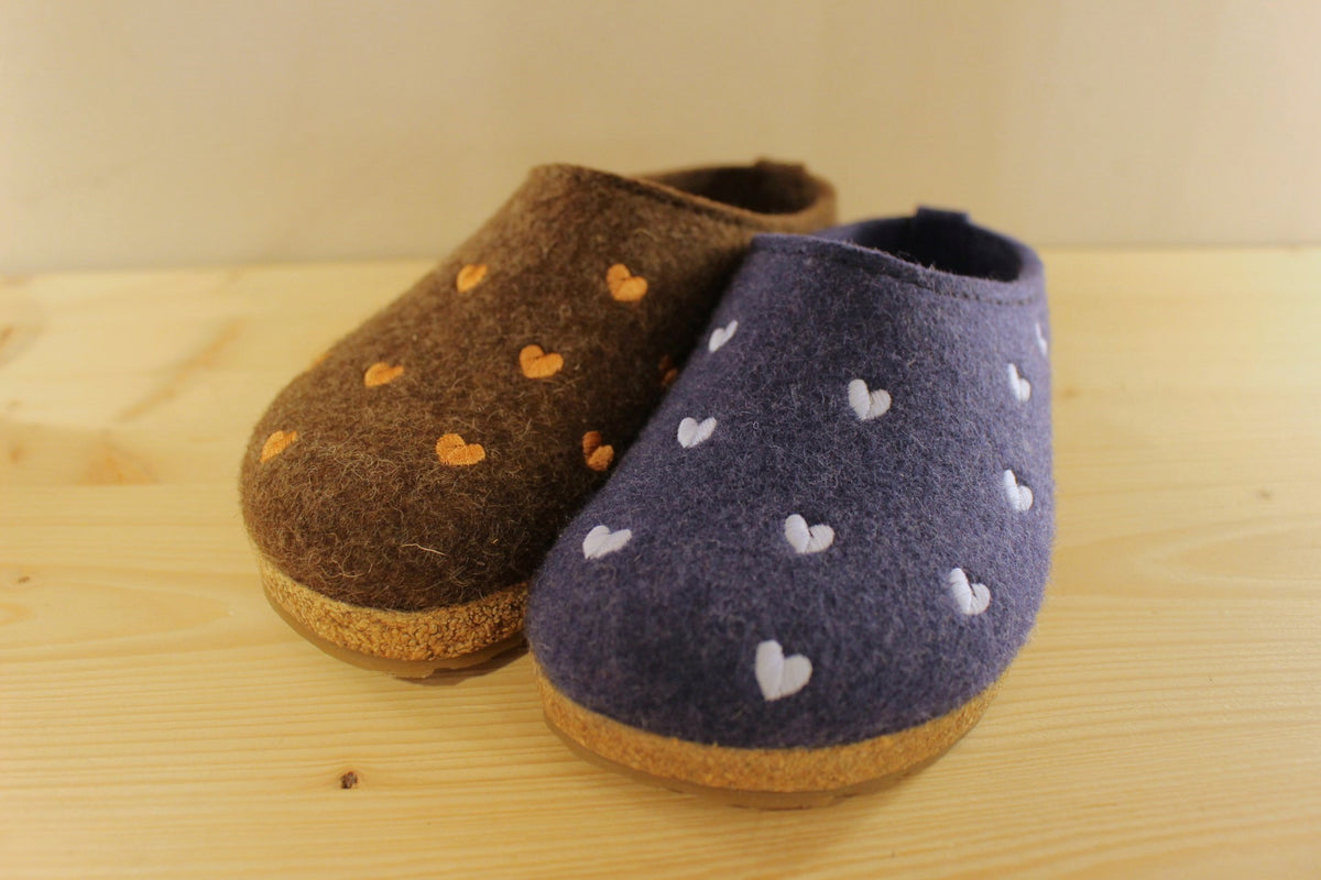 Chaussons HAFLINGER coupe sabot en pur laine de couleur chocolat avec des coeurs rose ou de couleur bleu jean avec des coeurs bleu ciel. Semelle externe en gomme et amorti liège 