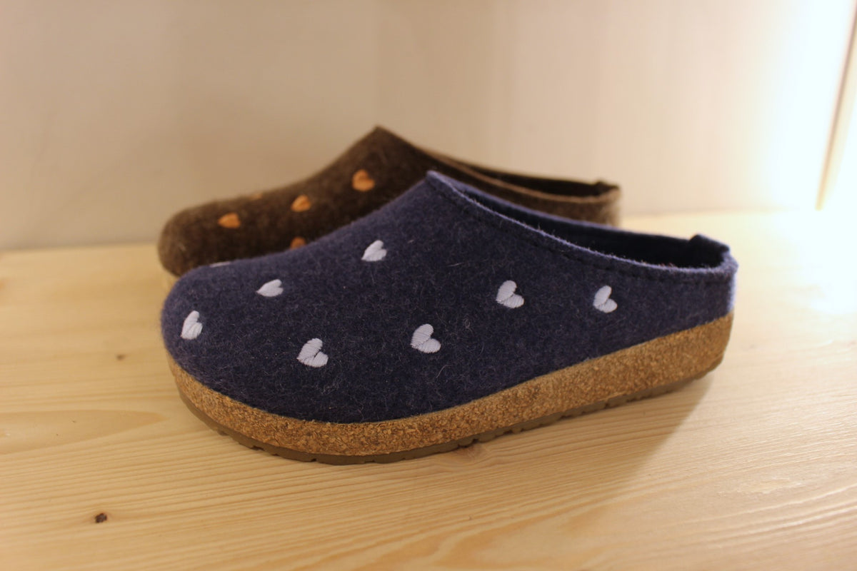 Chaussons HAFLINGER coupe sabot en pur laine de couleur chocolat avec des coeurs rose ou de couleur bleu jean avec des coeurs bleu ciel. Semelle externe en gomme et amorti liège 