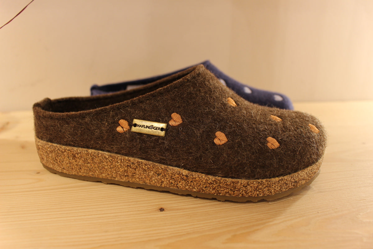 Chaussons HAFLINGER coupe sabot en pur laine de couleur chocolat avec des coeurs rose ou de couleur bleu jean avec des coeurs bleu ciel. Semelle externe en gomme et amorti liège 