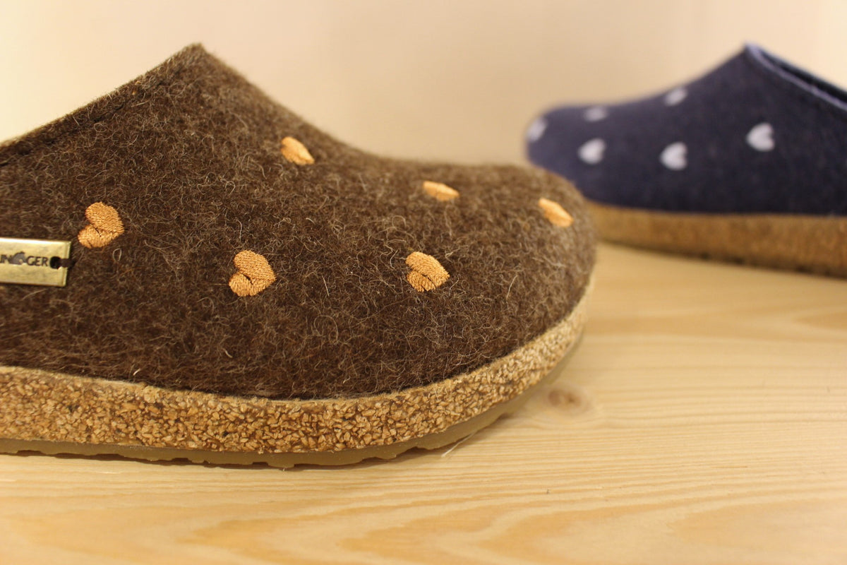 Chaussons HAFLINGER coupe sabot en pur laine de couleur chocolat avec des coeurs rose ou de couleur bleu jean avec des coeurs bleu ciel. Semelle externe en gomme et amorti liège 