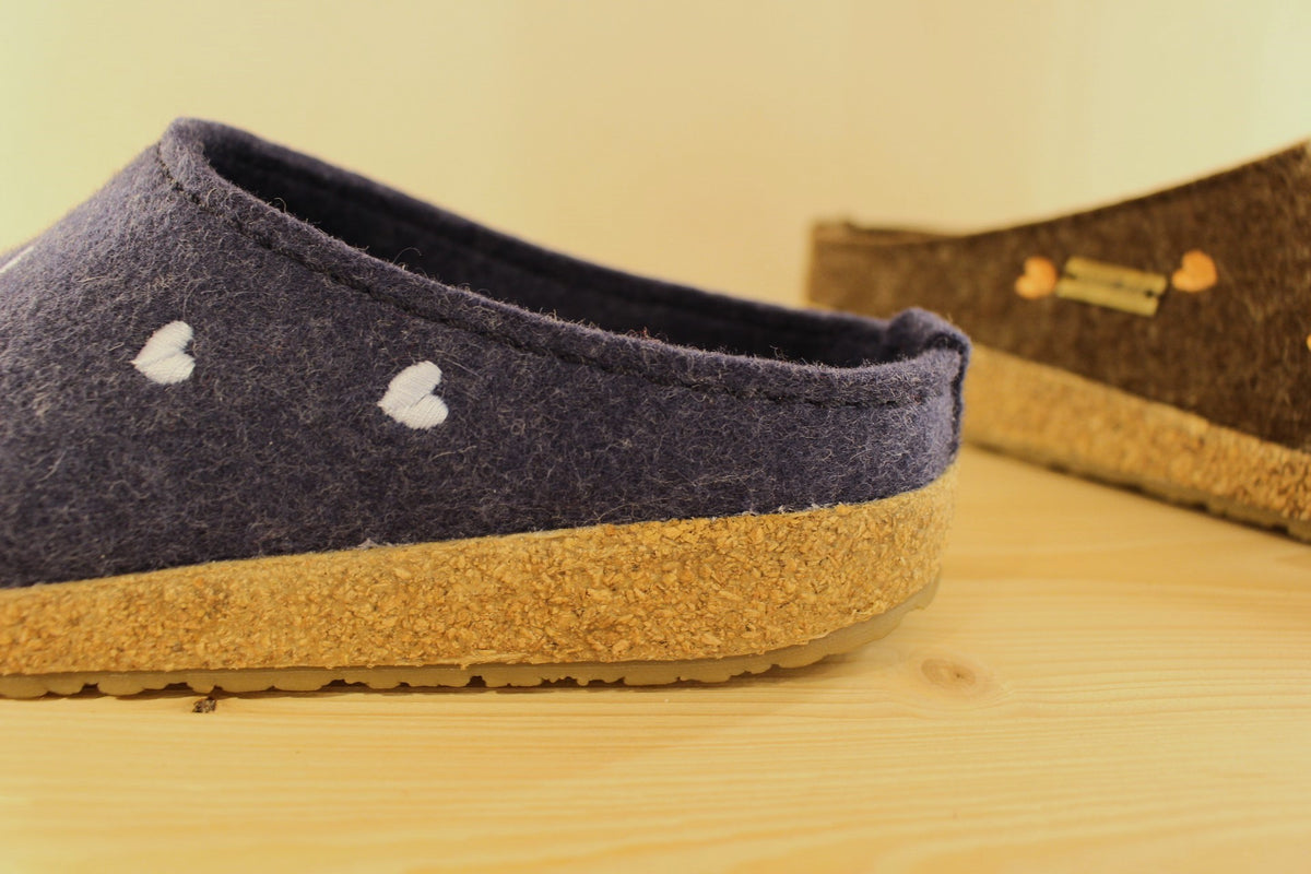 Chaussons HAFLINGER coupe sabot en pur laine de couleur chocolat avec des coeurs rose ou de couleur bleu jean avec des coeurs bleu ciel. Semelle externe en gomme et amorti liège 