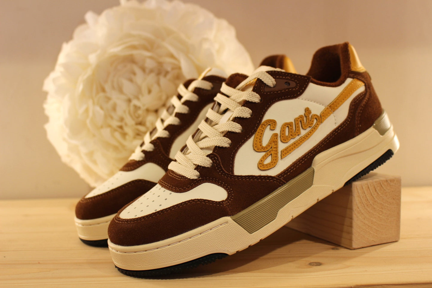  Sneakers homme en cuir lisse de couleur blanche et des touches de jaune, avec des parties en cuir velours marron sur l'avant et l'arrière du sneaker. 