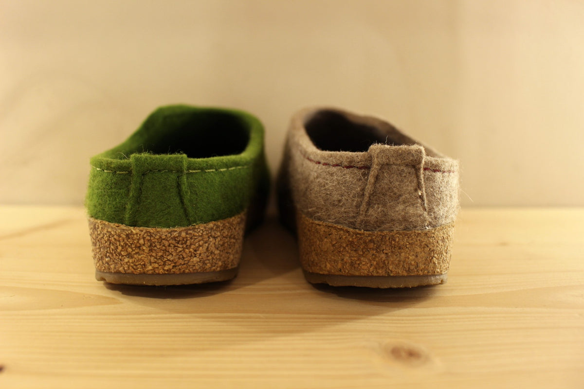  Chaussons HAFLINGER coupe sabot en pure laine de couleur vert ou beige. Déco de boutons colorés en laine sur le côté du coup de pied. Découpe asymétrique pour un bon maintien. 