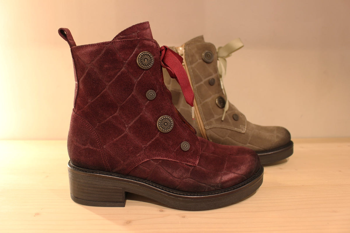Bottines Casta en cuir velours ras et brossé de couleur bordeaux ou de couleur kaki. Cuir imprimé et habillage bouton décoratif.