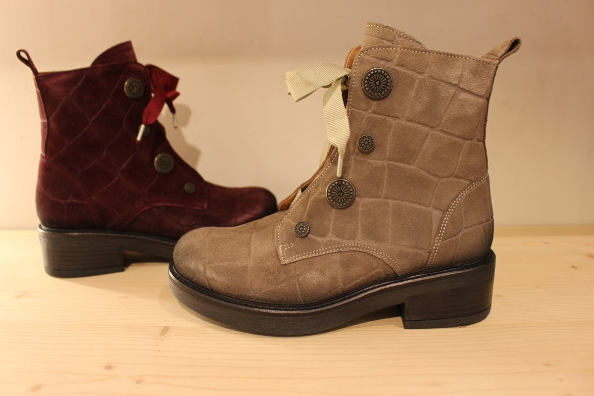 Bottines Casta en cuir velours ras et brossé de couleur bordeaux ou de couleur kaki. Cuir imprimé et habillage bouton décoratif.