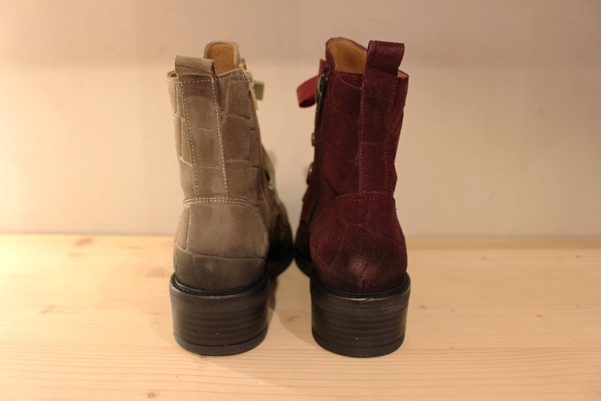 Bottines Casta en cuir velours ras et brossé de couleur bordeaux ou de couleur kaki. Cuir imprimé et habillage bouton décoratif.