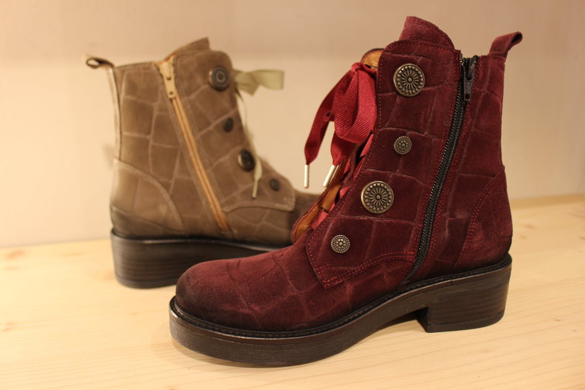 Bottines Casta en cuir velours ras et brossé de couleur bordeaux ou de couleur kaki. Cuir imprimé et habillage bouton décoratif.