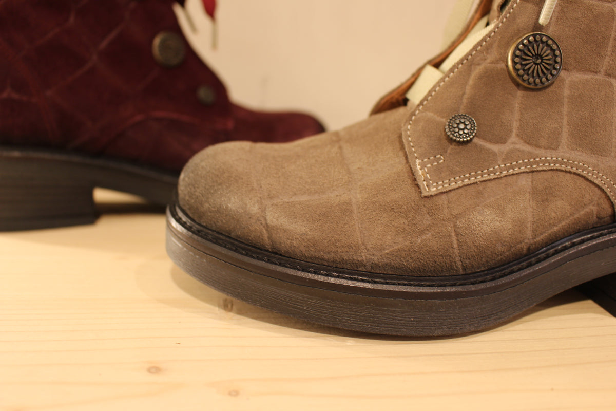 Bottines Casta en cuir velours ras et brossé de couleur bordeaux ou de couleur kaki. Cuir imprimé et habillage bouton décoratif.