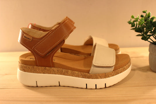 Sandales en cuir de couleur blanc cassé et camel. Serrage par deux scratchs, sur bride coup de pied et sur bride avant PIKOLINOS