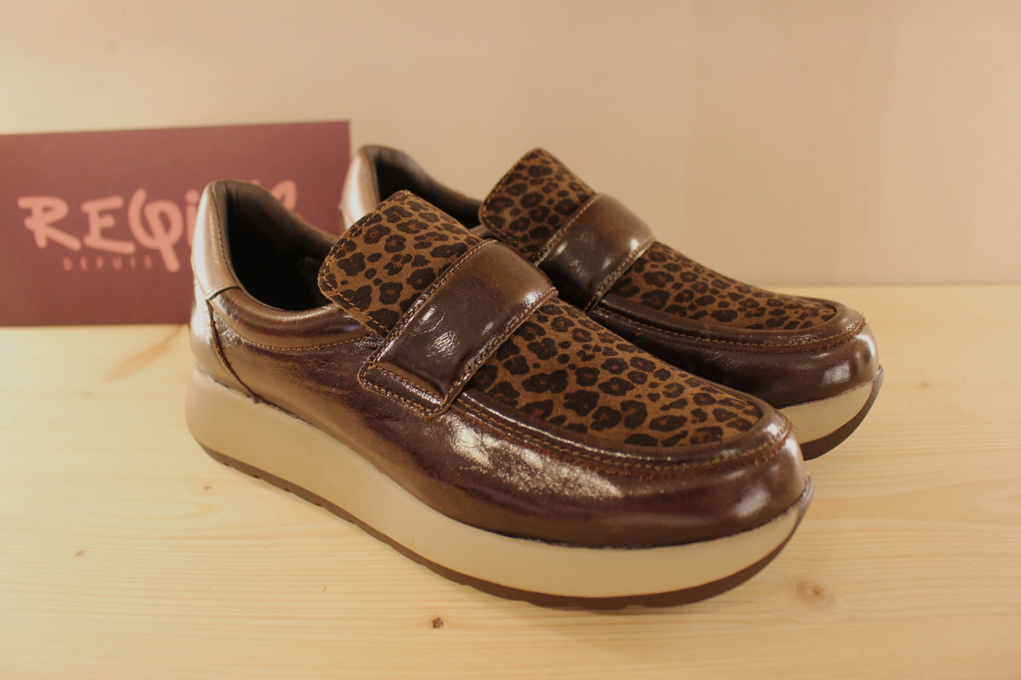 Mocassins REQINS en cuir vernis de couelur chocolat. Claque imprimée léopard ton sur ton. Métallisé bronze sur l'arrière